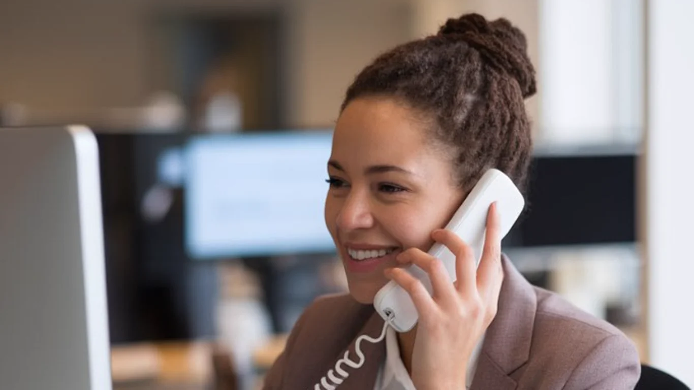 A professional legal intake specialist takes a client call at her office workstation.